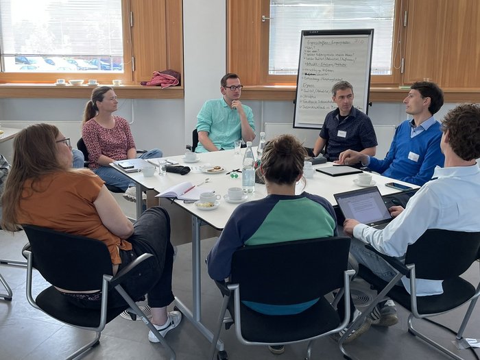 8 Personen sitzen um einen Tisch bei einem Workshop in Dessau.