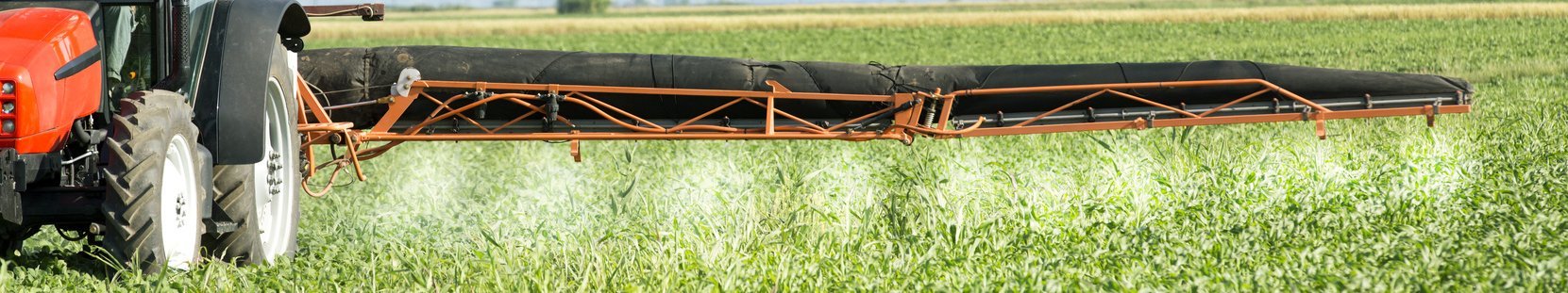 Traktor bringt Pflanzenschutzmittel auf Acker aus.