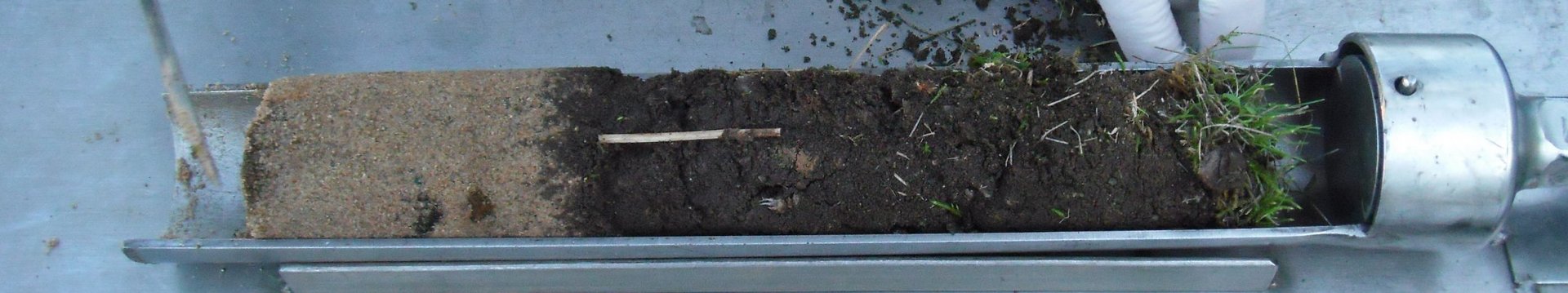 Eine Bodenprobe wird in einem Bohrstock gezeigt.