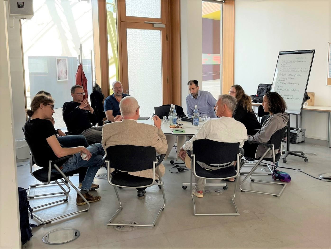 8 Personen sitzen um einen Tisch bei einem Workshop in Dessau.